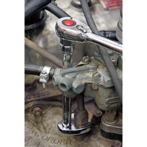 A close-up of a Sealey Crow's Foot Spanner from the 10-piece Metric set (AK598) being used to tighten a bolt on an engine part, with various hoses and mechanical components visible. Ideal for limited access applications, the Chrome Molybdenum steel enhances durability.