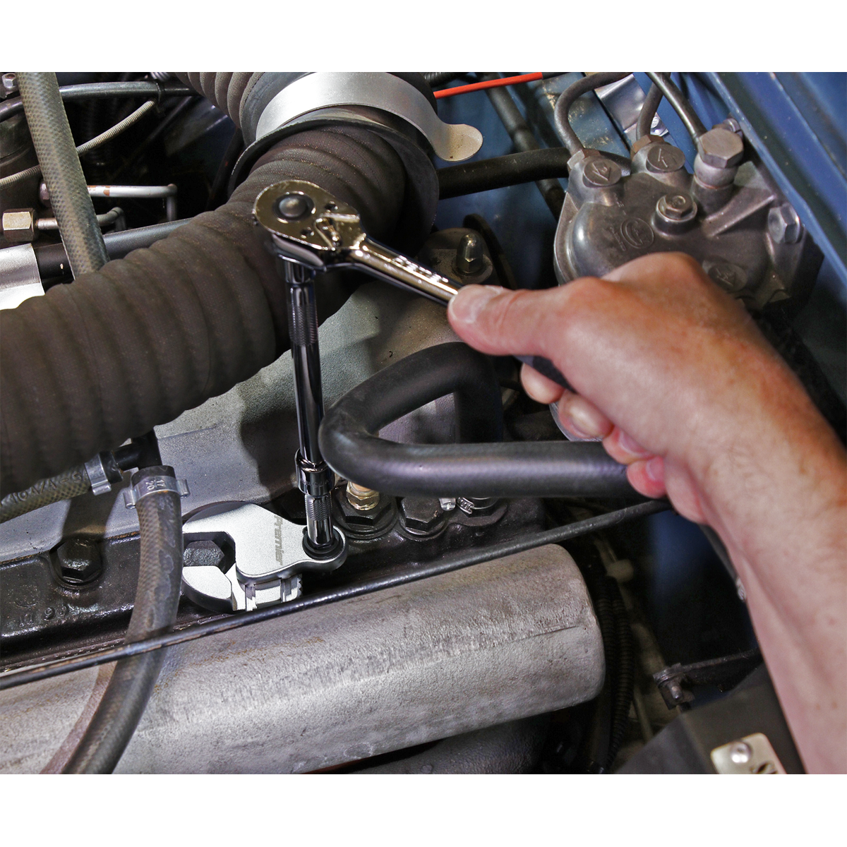 A hand using a Sealey Crow's Foot Wrench Adjustable 3/8" Sq Drive 6-30mm - AK5987, crafted from durable Chrome Molybdenum steel, to tighten or loosen a bolt on an engine component.