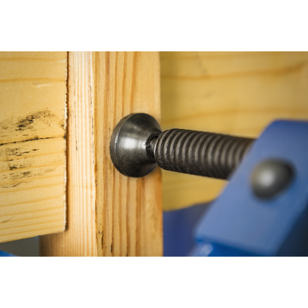 Close-up of a Sealey 100mm G-Clamp Quick Release (Model AK6004Q) securing two pieces of wood together, with the clamp's screw mechanism visible. The wood has some black markings.