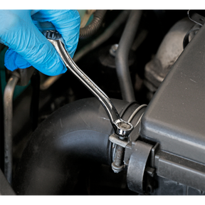 A gloved hand uses a Sealey Double End Ring Spanner Offset Stubby 10 x 13mm (AK63221) to tighten a bolt on a car engine component, showcasing the durability of Chrome Vanadium steel.