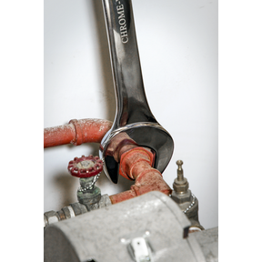 A Sealey Combination Spanner Super Jumbo 42mm - AK632442 tightens a rusted red pipe connection, next to a valve with a red handle and a gray metallic component, illustrating the reliability of Premier Hand Tools for both agricultural and industrial use.