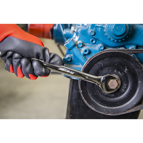 A gloved hand from the Sealey Combination Spanner Set 12pc - Metric - AK63265 uses a wrench to tighten a bolt on a mechanical assembly, showcasing the reliable strength of chrome vanadium steel.