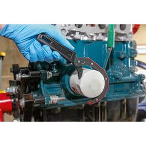 With a firm grip, a gloved hand uses the Sealey Oil Filter Wrench Ø75-95mm - AK6420 to remove an oil filter from a blue engine block.