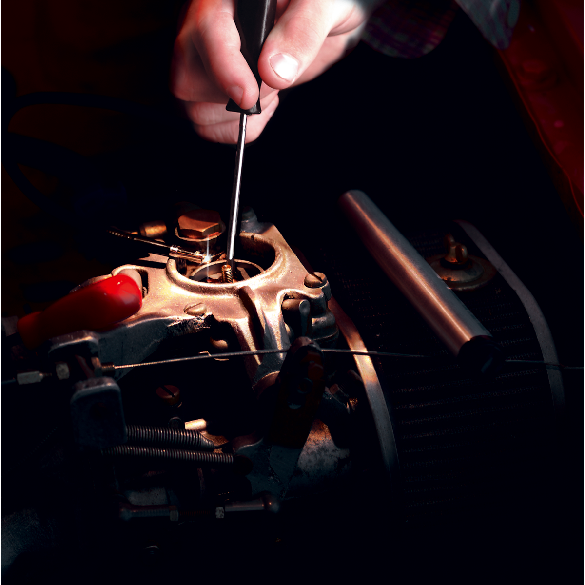 A person uses the Sealey Flexible Inspection Mirror with Light - AK650 to adjust the components of an engine part under dim lighting.