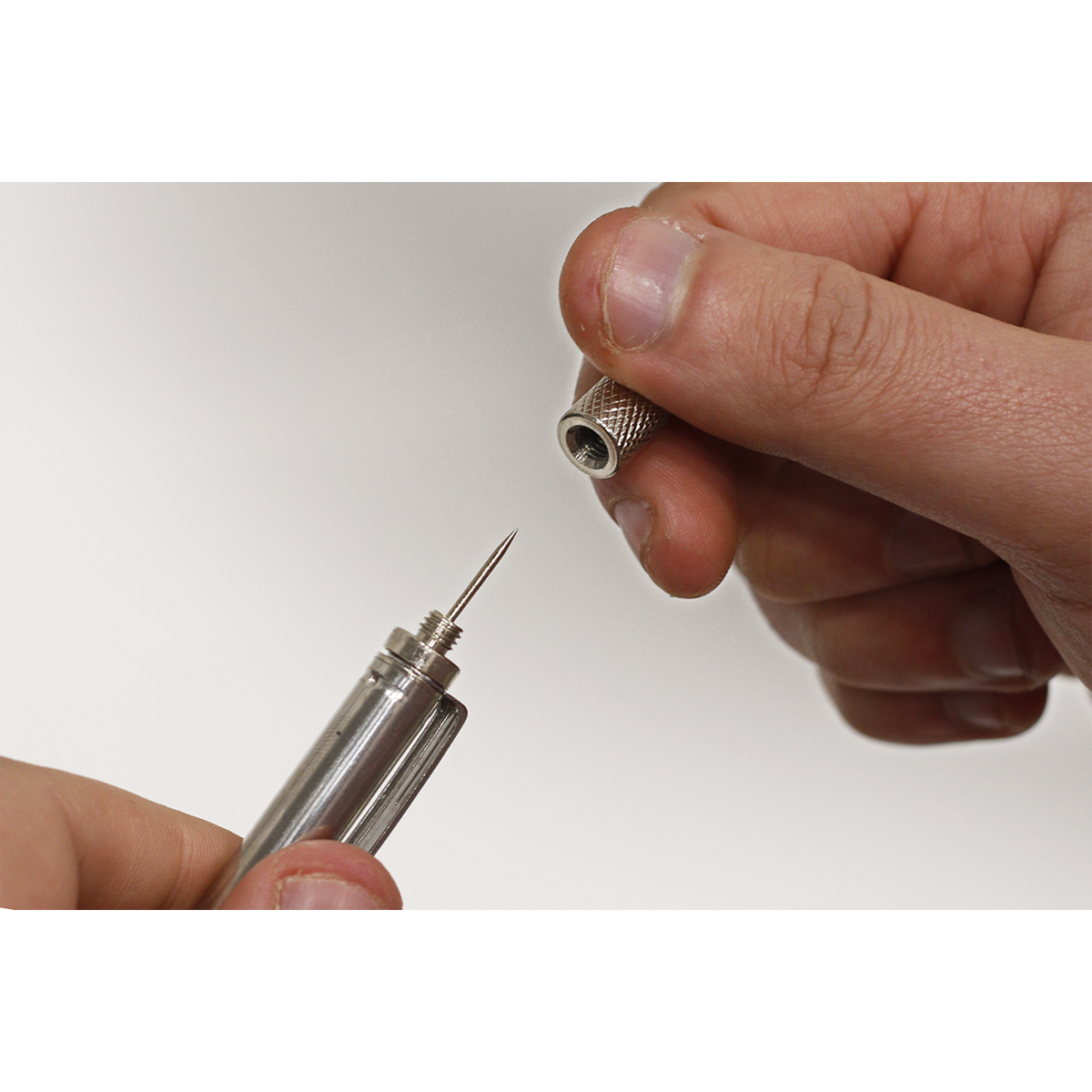 Close-up of hands holding and assembling a Sealey Magnetic Pick-Up Tool 1.6kg Capacity - AK6516, with one hand screwing a cap onto the needle-like device.