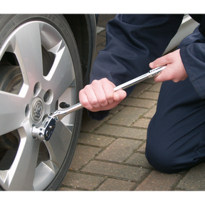 The person is using a Sealey Ratchet Wrench Flexi-Head 445mm 1/2"Sq Drive Pear-Head Flip Reverse - AK662F to tighten a lug nut on a car wheel, confident in the quality backed by a lifetime guarantee.