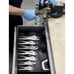 A person wearing blue gloves uses a wrench at a workbench, with an open drawer showcasing organized clamp pliers and Sealey's Locking Pliers Set 10pc - AK6800 for professional use.