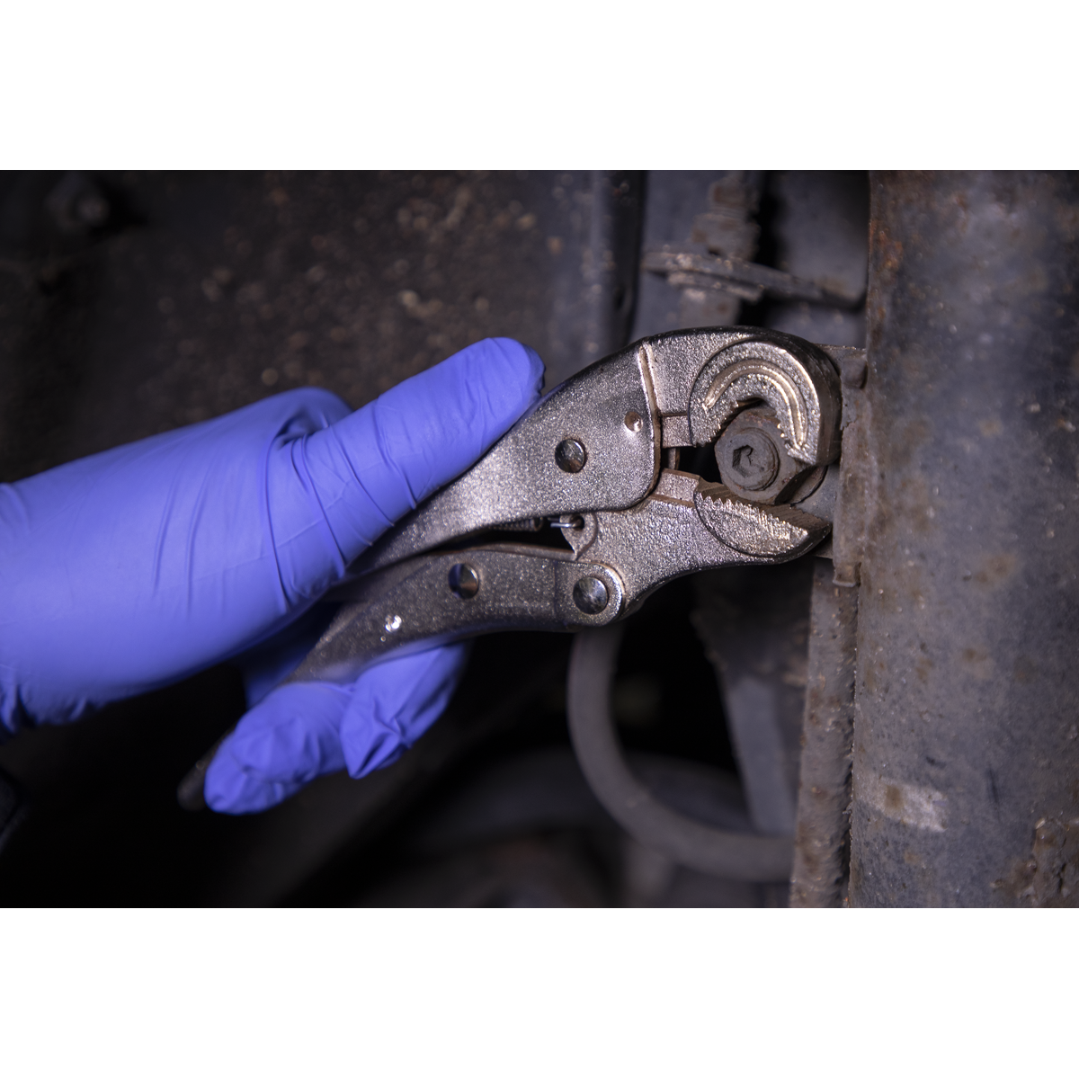 A gloved hand uses the Sealey Locking Pliers Round Jaws 195mm 0-35mm Capacity - AK6871 to tighten a bolt on a piece of machinery.