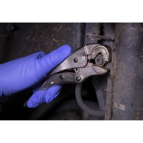 A gloved hand uses the Sealey Locking Pliers Round Jaws 195mm 0-35mm Capacity - AK6871 to tighten a bolt on a piece of machinery.