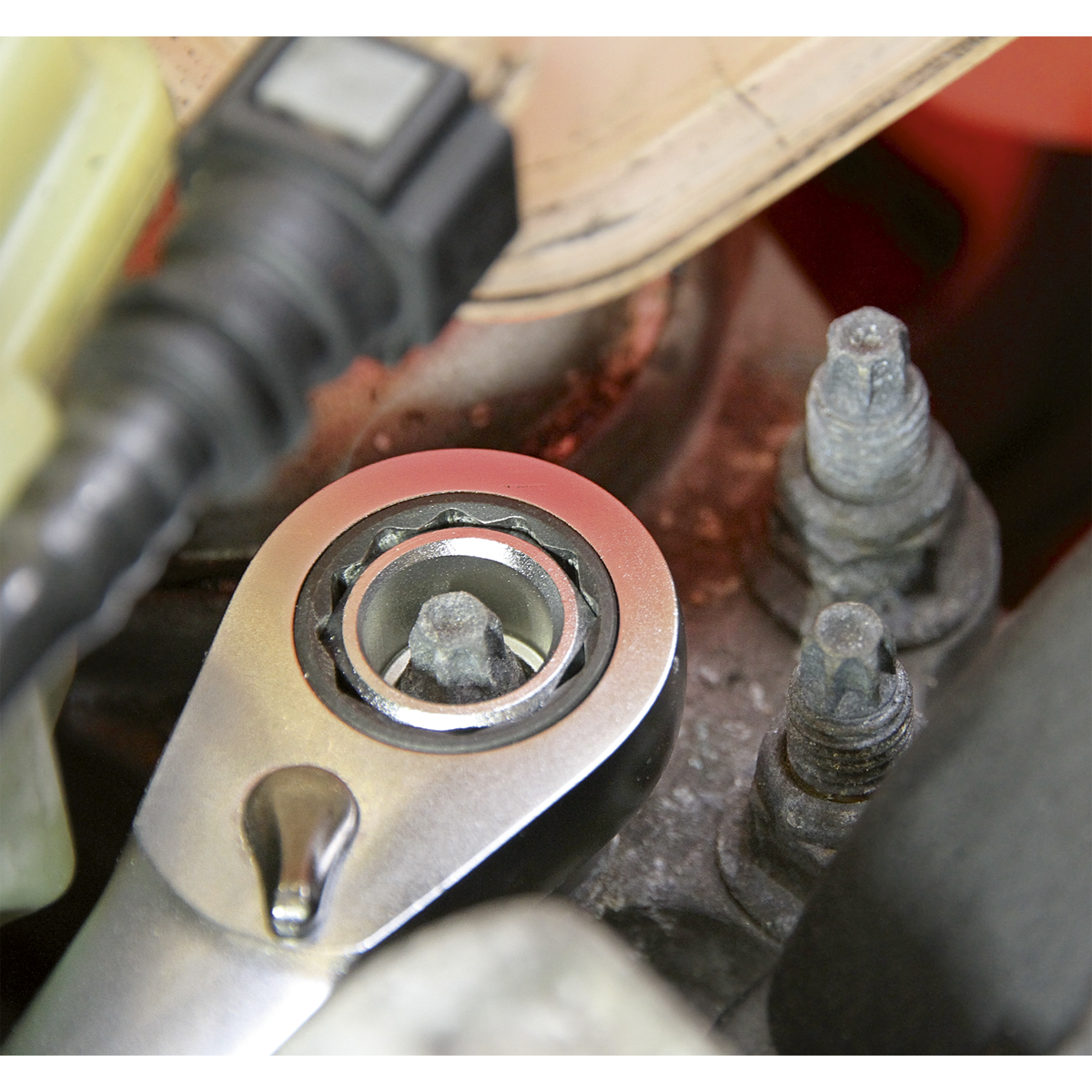 Close-up of a Sealey AK6926 Go-Through Low Profile WallDrive® Metric Socket Set fitting onto a bolt with a hexagonal head, positioned among other bolts and car engine components, showcasing the durability of Chrome Vanadium steel.