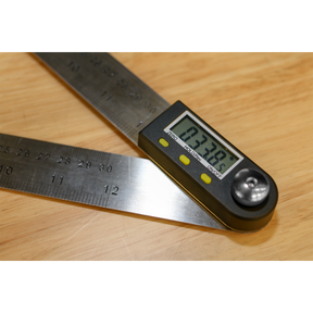 The Sealey Digital Angle Rule 300mm (12") - AK7300 features an LCD display that shows a precise measurement of 137.9 degrees. Ideal for woodworking projects, it is used on a wooden surface.