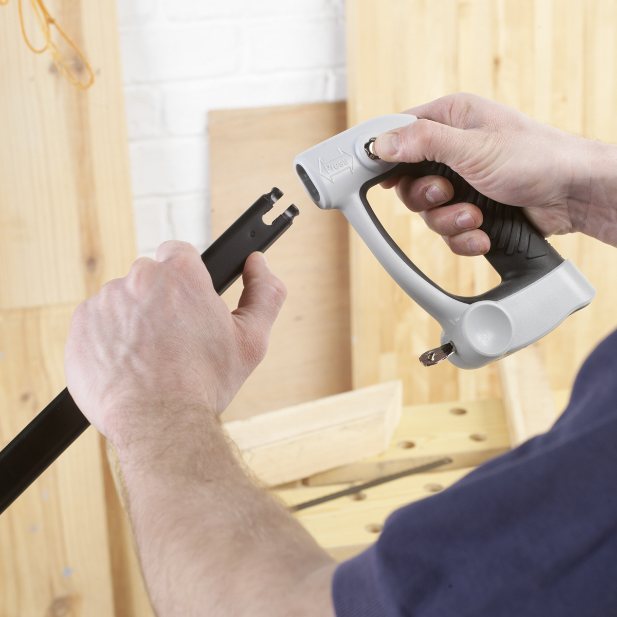 A woodworker is using the Sealey Hacksaw Adjustable Blade Professional 300mm - AK8684, featuring a gray and black composite handle, to connect it precisely and durably to a high carbon steel blade.