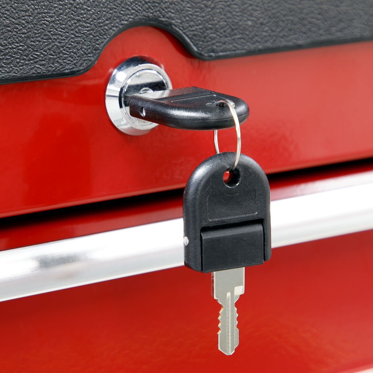 Close-up of a key inserted in a red Sealey Rollcab 7 Drawer Lock, attached to a black plastic keychain with perforated side panels.