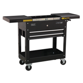 The Sealey Mobile Tool & Parts Trolley - Black - AP705MB features a single drawer, an open storage space beneath, and fold-out side trays. Constructed from heavy gauge steel, it comes with a lockable sliding top and heavy-duty ball-bearing slides. The trolley is equipped with four caster wheels and caution markings on the side trays.