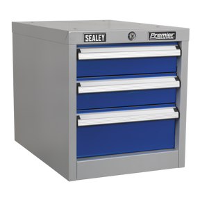The "Sealey Industrial Triple Drawer Unit for API Series Workbenches - API16" is a gray metal toolbox featuring three blue drawers with heavy-duty drawer slides and a lockable top, ideal for an industrial workbench setting.