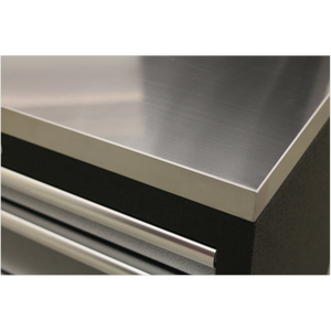 Close-up of a Sealey Stainless Steel Worktop 680mm - APMS50SSA with a corner of a black drawer unit below it. The stainless steel worktop has a brushed finish, and the drawer unit, part of the APMS Floor Cabinets collection, features a horizontal handle.