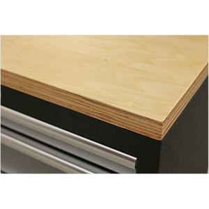 Close-up of a Pressed Wood Worktop 680mm - APMS50WA by Sealey, showcasing its smooth, light-colored surface and layered edges, positioned above a black APMS Floor Cabinet with metal handles. Enjoy peace of mind with the 5 Year Guarantee on every Sealey Pressed Wood Worktop.