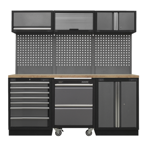 The Superline PRO® 2.04m Storage System - Pressed Wood Worktop - APMSSTACK12W by Sealey is a black and gray garage workbench known for its heavy-duty construction. It comes equipped with multiple drawers, overhead cabinets, and a pegboard backsplash for tools. Additionally, the workbench features a wooden countertop and includes a modular rolling cabinet.
