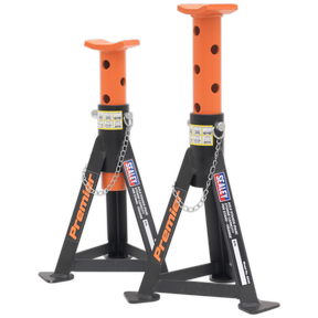 Two orange "Sealey" axle stands, each with a 3-tonne capacity, feature a heavy-duty steel frame and multi-position pin load support. The stands have adjustable heights with locking pins and a chain.