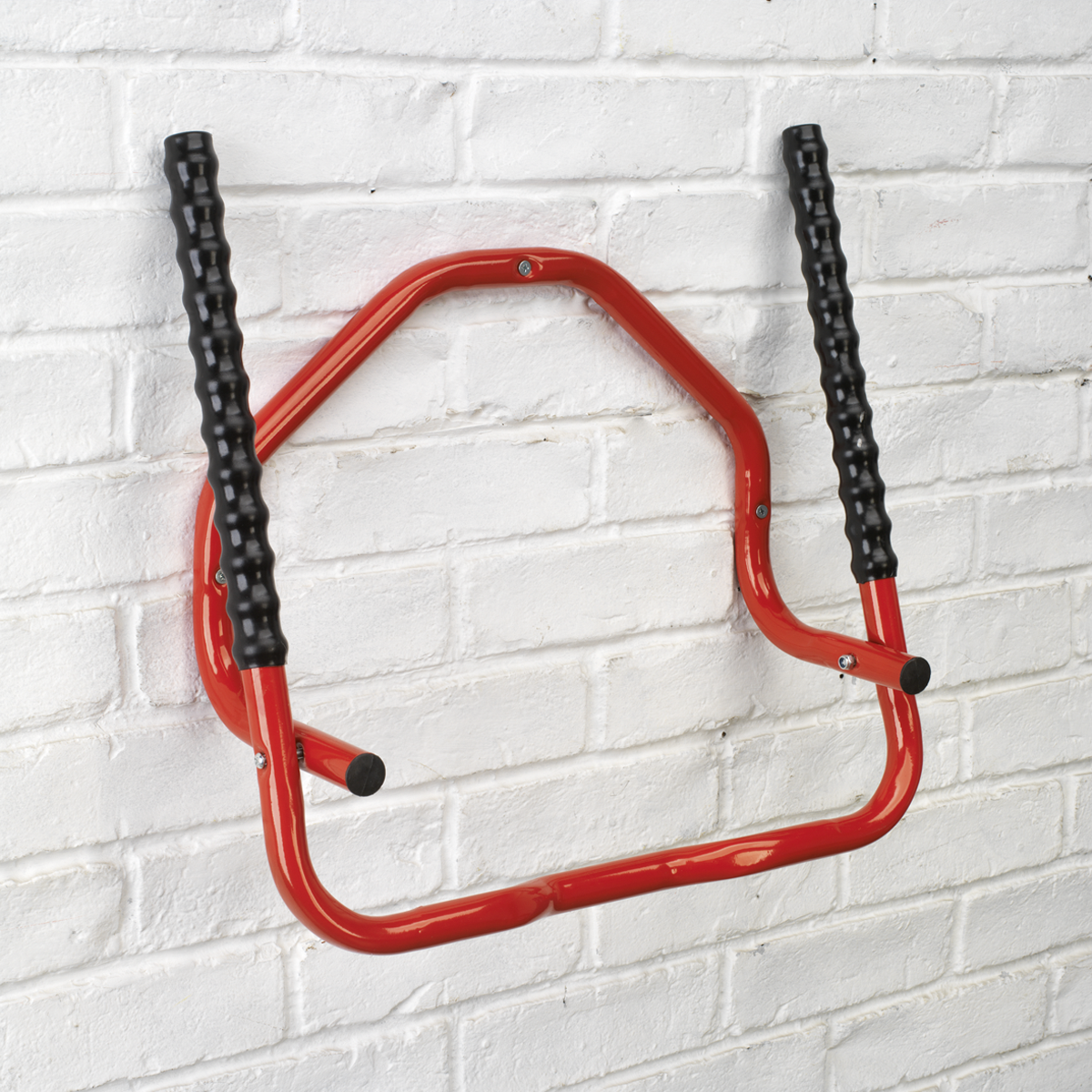 The Sealey Bicycle Rack Wall Mounting Folding - BS7, featuring red arms with black grips, installed on a white brick wall, offers compact storage and supports two bicycles.