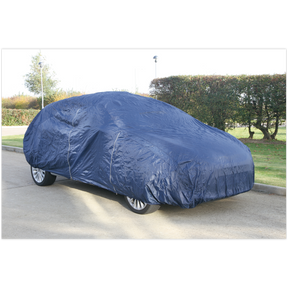 A parked car is completely covered with the Sealey Car Cover Lightweight Large 4300 x 1690 x 1220mm - CCEL, made of lightweight material on a street lined with greenery and a hedge in the background, ensuring dust protection.