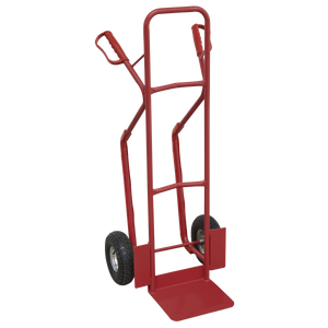 The Sealey Sack Truck with Pneumatic Tyres 300kg Capacity - CST999 is a red hand truck equipped with two black pneumatic wheels and a robust metal frame, designed to assist in moving heavy objects. Ideal for uneven surfaces, it features air-filled pneumatic tires that provide smoother handling over rough terrain.