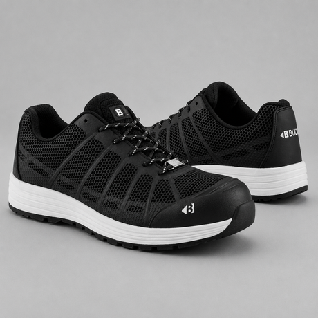 A pair of black protective work shoes with white midsoles, shown from the side and back on a neutral gray background.