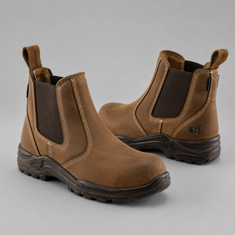 A pair of brown leather Chelsea-style work boots with dark brown elastic side panels and dark soles, shown on a neutral gray background.