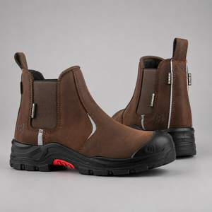 A pair of brown Chelsea-style work boots with black soles and a small red accent on the side, photographed on a neutral gray background.