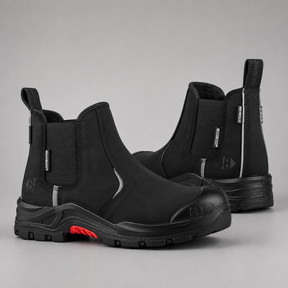 A pair of black Chelsea-style work boots with elastic side panels, a protective toe cap, and a rugged sole, shown on a neutral gray background.