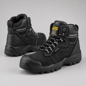 A pair of black high-top safety work boots with silver laces and a yellow and black tongue label, displayed on a neutral gray background.