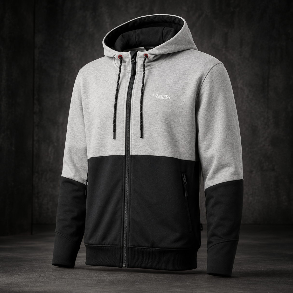 A men's colorblock zip-up hoodie with a light gray upper body and hood, black lower body and sleeves, and a black front zipper, shown against a dark textured studio background.