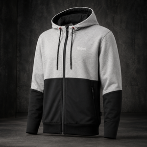 A men's colorblock zip-up hoodie with a light gray upper body and hood, black lower body and sleeves, and a black front zipper, shown against a dark textured studio background.