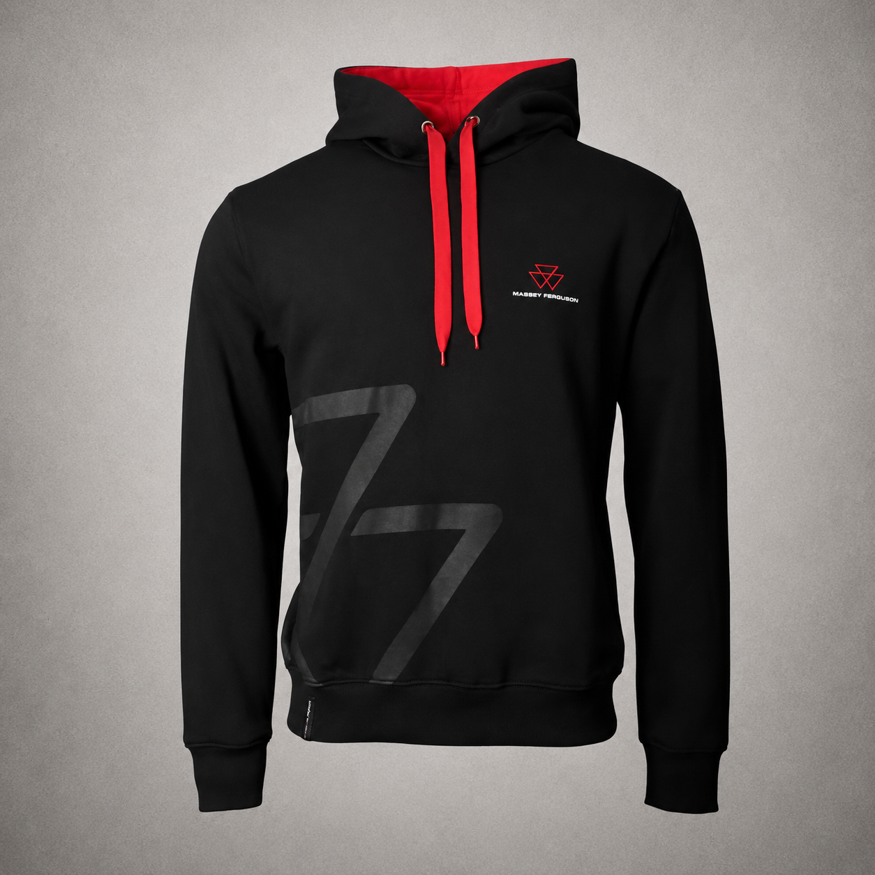 A black pullover hoodie with a red hood lining and red drawstrings, featuring a large dark gray graphic on the front and a small red and white chest logo, displayed on a textured gray background.
