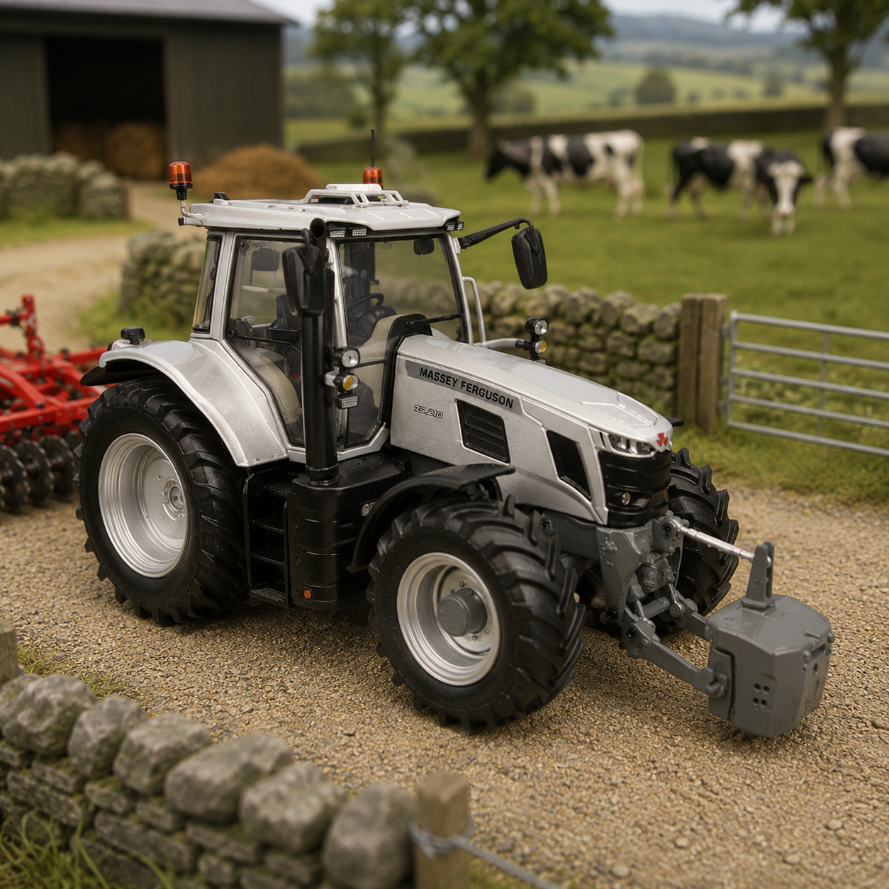 A silver and black toy tractor with a front attachment, shown outdoors on a gravel path with a blurred farm background including cows, trees, and a barn.
