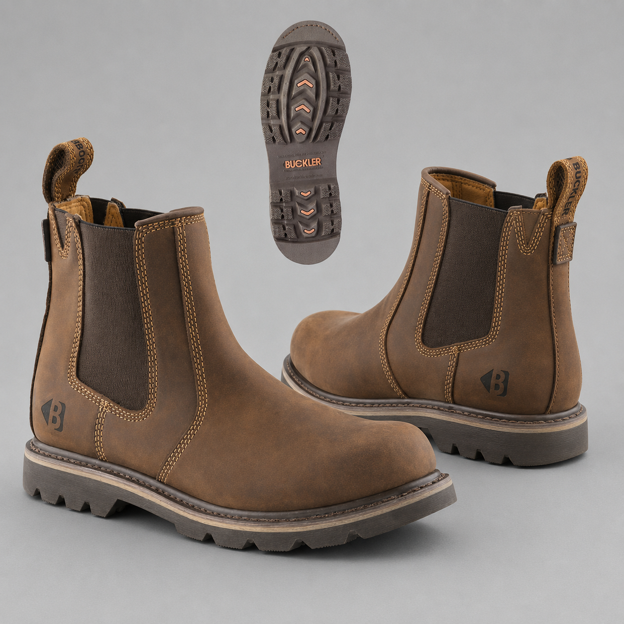 A pair of brown leather Chelsea-style boots with dark elastic side panels and rugged lug soles, shown on a light gray background. One boot is angled to show the side and front, the second boot shows the outer side and sole, and a separate inset shows the outsole tread with the brand name Buckwild visible.