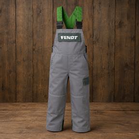 Gray Fendt bib overalls with green suspenders and a green chest patch displaying the FENDT logo, shown against a dark wood plank background.