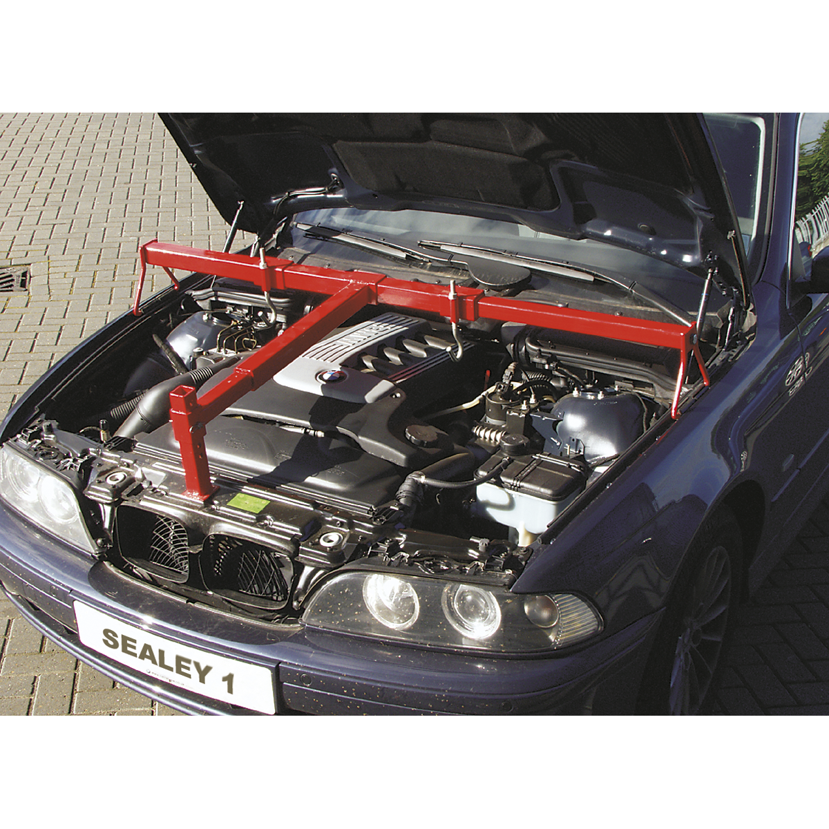 A car with an open hood revealing an engine being supported by a red, height-adjustable foot and the Sealey Engine Support Beam 600kg Heavy-Duty - ES600.