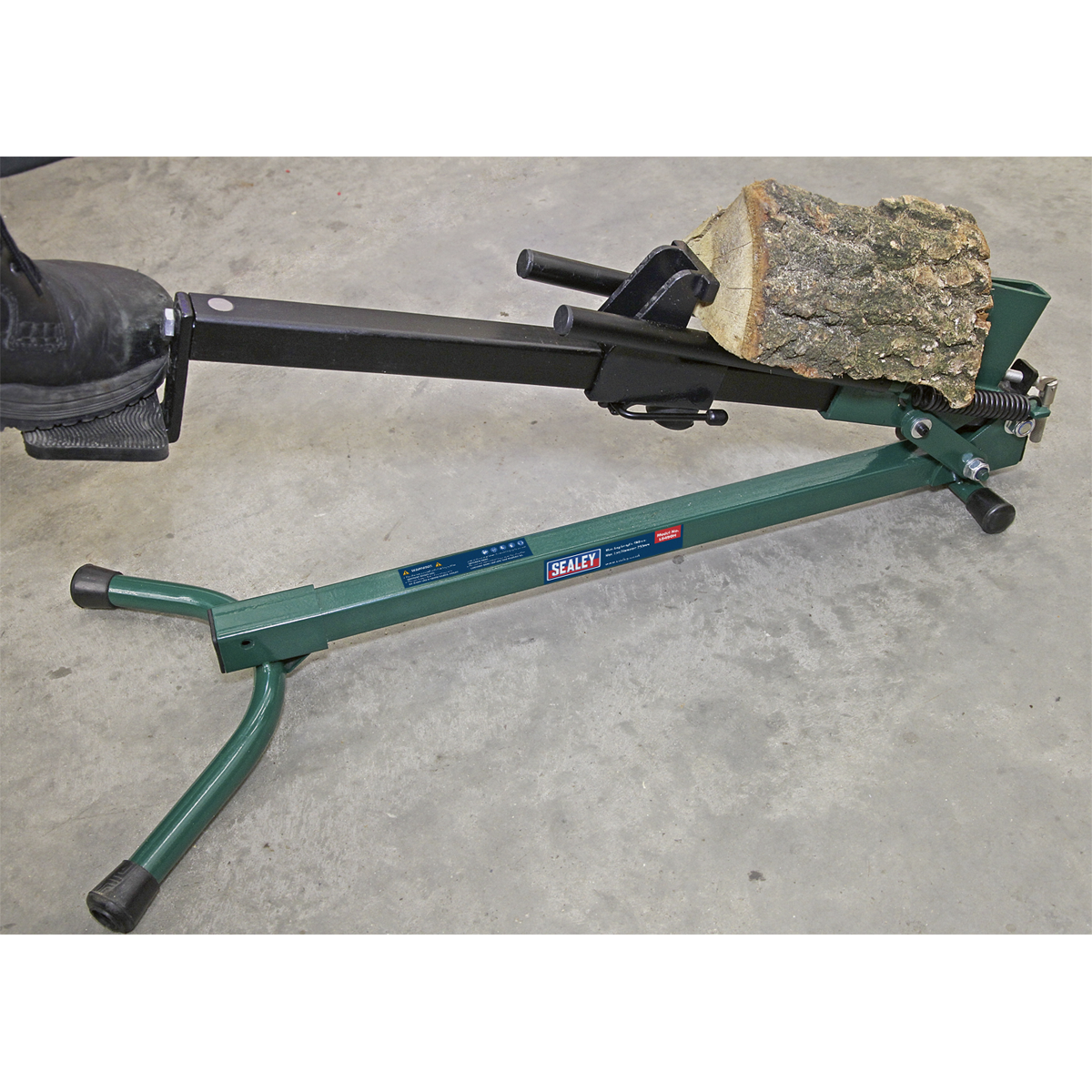 With a piece of wood placed in the splitting area, the Sealey Log Splitter Foot Operated - Horizontal - LS450H, set on a concrete floor, allows for convenient firewood splitting.