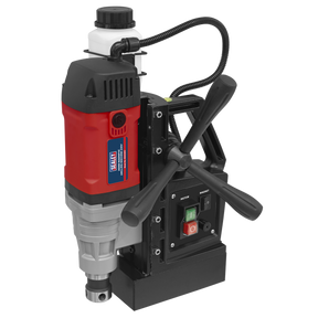 The Sealey Magnetic Drilling Machine 35mm 230V - MAG230V is a red and black magnetic drill press with high-quality components, control switches, adjustment handles, an attached fluid bottle, and power cables. It is ideal for working with ferrous metal.