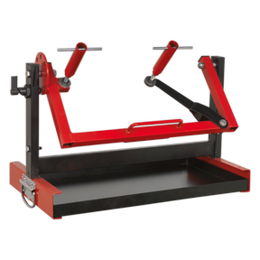 The Sealey Motorcycle Engine Stand - Single/Twin Cylinder - MES01 is a red and black mechanical device featuring adjustable arms, a rectangular base, and an integrated utility tray, designed for securely mounting or holding objects in place.