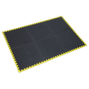 The Sealey Interlocking EVA Foam Workshop Mat Set 1240 x 1825mm with Hi-Vis Edges - MIC1218Y3 features a black rectangular mat with a yellow border and interlocking edges, designed for enhanced fatigue relief.