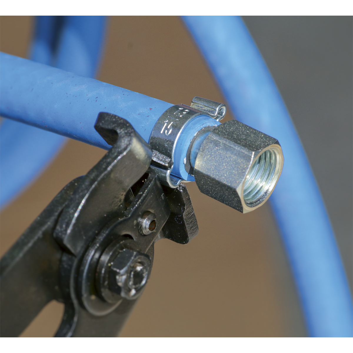 Close-up of a blue hydraulic hose secured with a Sealey O-Clip Double Ear Ø9-11mm from the OCDE911 pack of 25, being tightened by a pair of pliers.