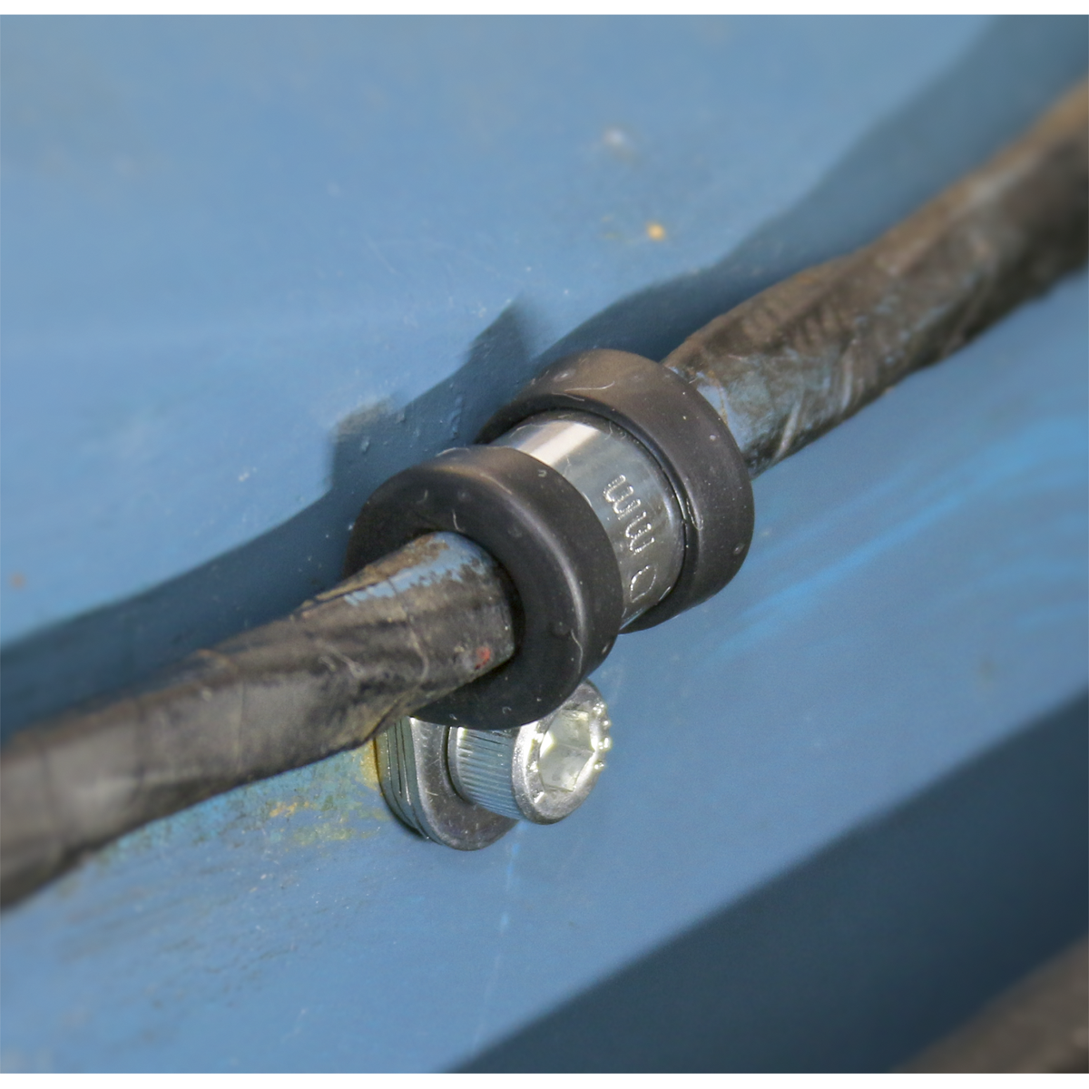 Close-up of a black cable secured to a blue surface with a Sealey P-Clip Rubber Lined Ø29mm (Pack of 25 – PCJ29) and screw.