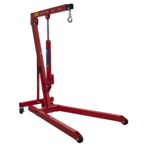 The Sealey Low Profile Engine Crane 0.5 Tonne - PH5 is a red hydraulic engine crane featuring a lifting hook on top and supported by four heavy-duty castors for enhanced mobility, making it both lightweight and manoeuvrable.