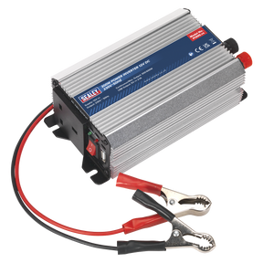 Image of the Sealey Power Inverter 300W 12V DC - 230V~50Hz - PI300 featuring a silver ribbed casing, attached red and black cables with alligator clips, and a USB port. This versatile inverter provides a reliable 230V power supply for various devices.