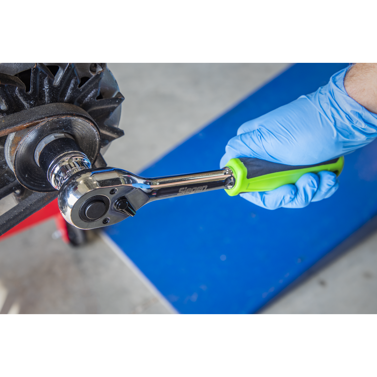 A gloved hand uses a 72-Tooth pear-head ratchet wrench from the Sealey Socket Set 12pc 1/2"Sq Drive WallDrive® Metric (Model S01244) to tighten or loosen a bolt on machinery, ensuring precision.