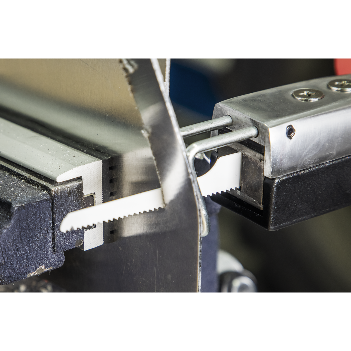 Close-up of a metal bandsaw equipped with Sealey Air Saw Blades Mixed - Pack of 15 - SA34MIX, featuring fine 24tpi teeth, slicing through a piece of clamped aluminum.