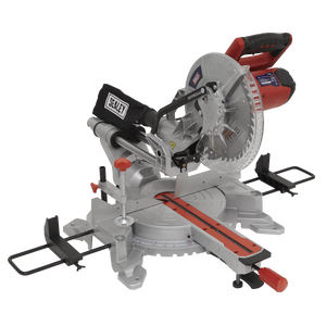 Introducing the Sealey Sliding Compound Mitre Saw Ø255mm - SMS255. This miter saw is mounted on a sturdy base and features a sleek silver body with striking red accents and a comfortable black handle. It comes equipped with a circular multipurpose blade for versatile cutting tasks, and the attached black dust collection bag prominently displays the "Sealey" logo. Powered by an impressive 2000W motor, this saw ensures efficient and precise cutting every time.