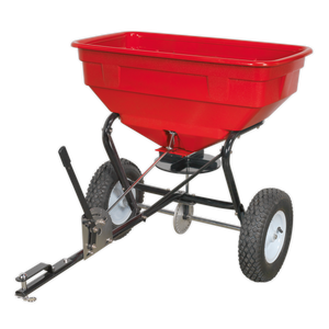 The Sealey Broadcast Spreader 57kg Tow Behind - SPB57T features an adjustable feed system and is designed with a red body, black frame, and two large white heavy-duty pneumatic tyres.